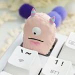 Unique handcrafted artisan resin keycap from various angles, showcasing a whimsical vibrant little monster creature embedded in colorful design.