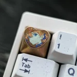 Artistic close-up of the handcrafted Asuka Titanium Heart ESC keycap, revealing the premium metallic luster and iconic fandom heart motif.
