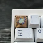 Handcrafted Asuka Titanium Heart ESC keycap viewed from multiple angles, highlighting its iconic colors and meticulously crafted metallic finish.