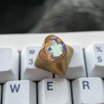 Product gallery of the handcrafted Asuka Titanium Heart ESC keycap, showcasing its iconic colors and metallic titanium surface from various premium angles.