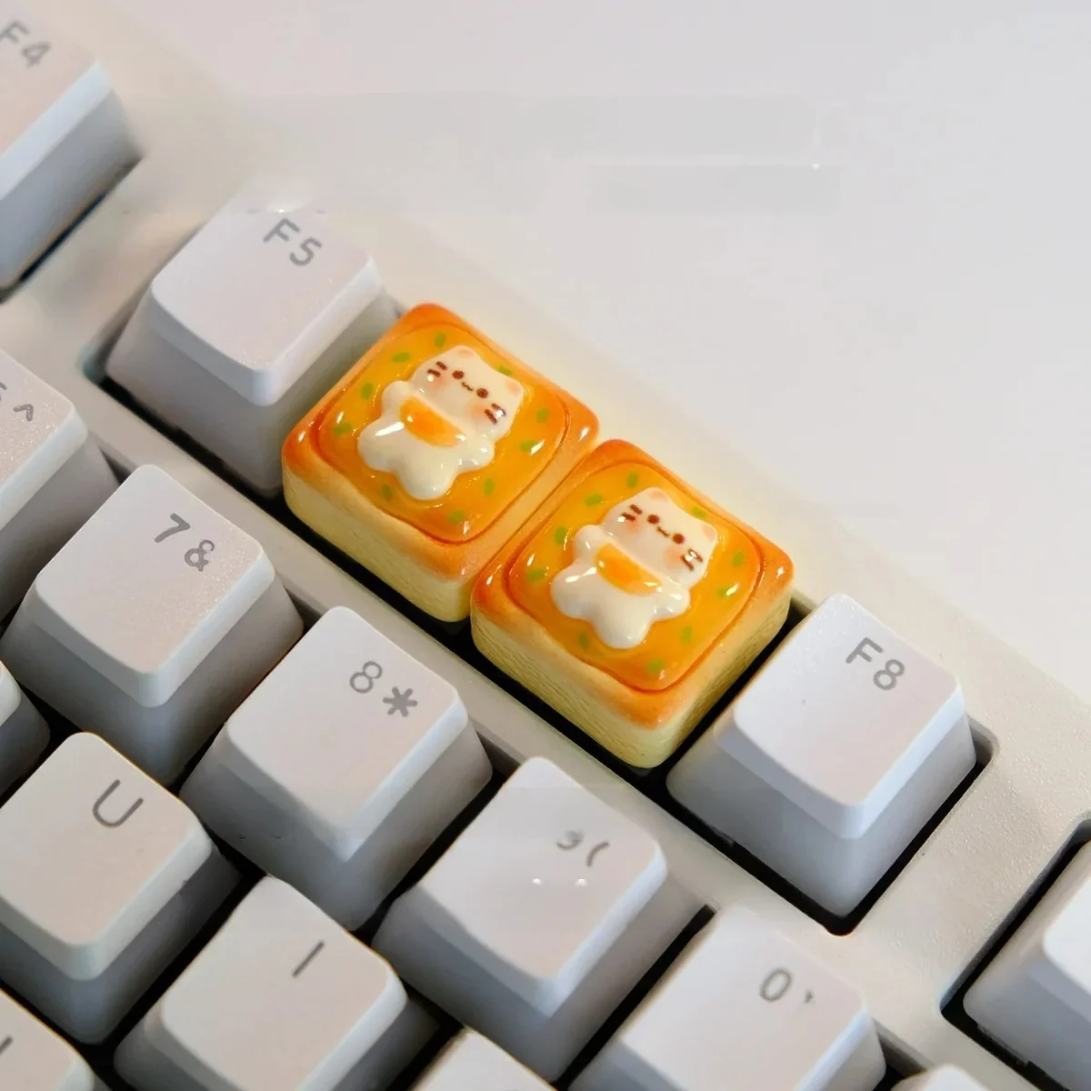 Close-up of a handcrafted whimsical cat toast keycap from a side angle, showcasing the adorable sleepy cat nestled on golden toast.