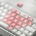 Close-up of ethereal translucent ceramic heart supplement keycaps set, a 21-piece set with delicate cherry blossom and heart motifs, showcasing artisan craftsmanship.