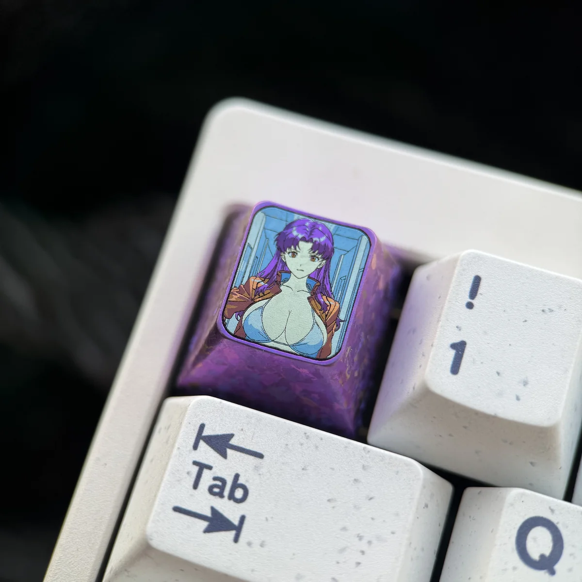 Close-up views of the iconic Misato Katsuragi Evangelion titanium keycap from multiple angles, highlighting its sleek finish and vibrant character art.
