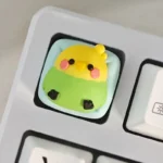 A collection of whimsical handcrafted parakeet resin keycaps from various angles, showcasing vibrant colors and intricate details as a unique keyboard.