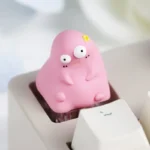 Close-up of a vibrant handcrafted Ugly Cute resin keycap, showcasing its unique texture and quirky abstract character design from multiple angles.