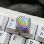 Unique handcrafted Damascus titanium ESC keycap shown from various angles, highlighting its intricate patterns and iridescent hues.