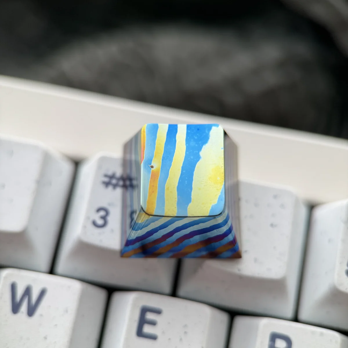 Multiple angles of a unique handcrafted Damascus titanium ESC keycap, emphasizing its intricate patterns, iridescent finish, and fusion of ancient craftted.