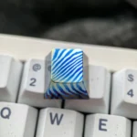 Close-up views of a unique handcrafted Damascus Titanium ESC keycap, showcasing its intricate patterns and iridescent titanium hues from multiple angles.