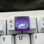 An artistic shot of the premium Gengar titanium low-profile keycap, revealing its intricately sculpted mischievous character from a different perspective view.