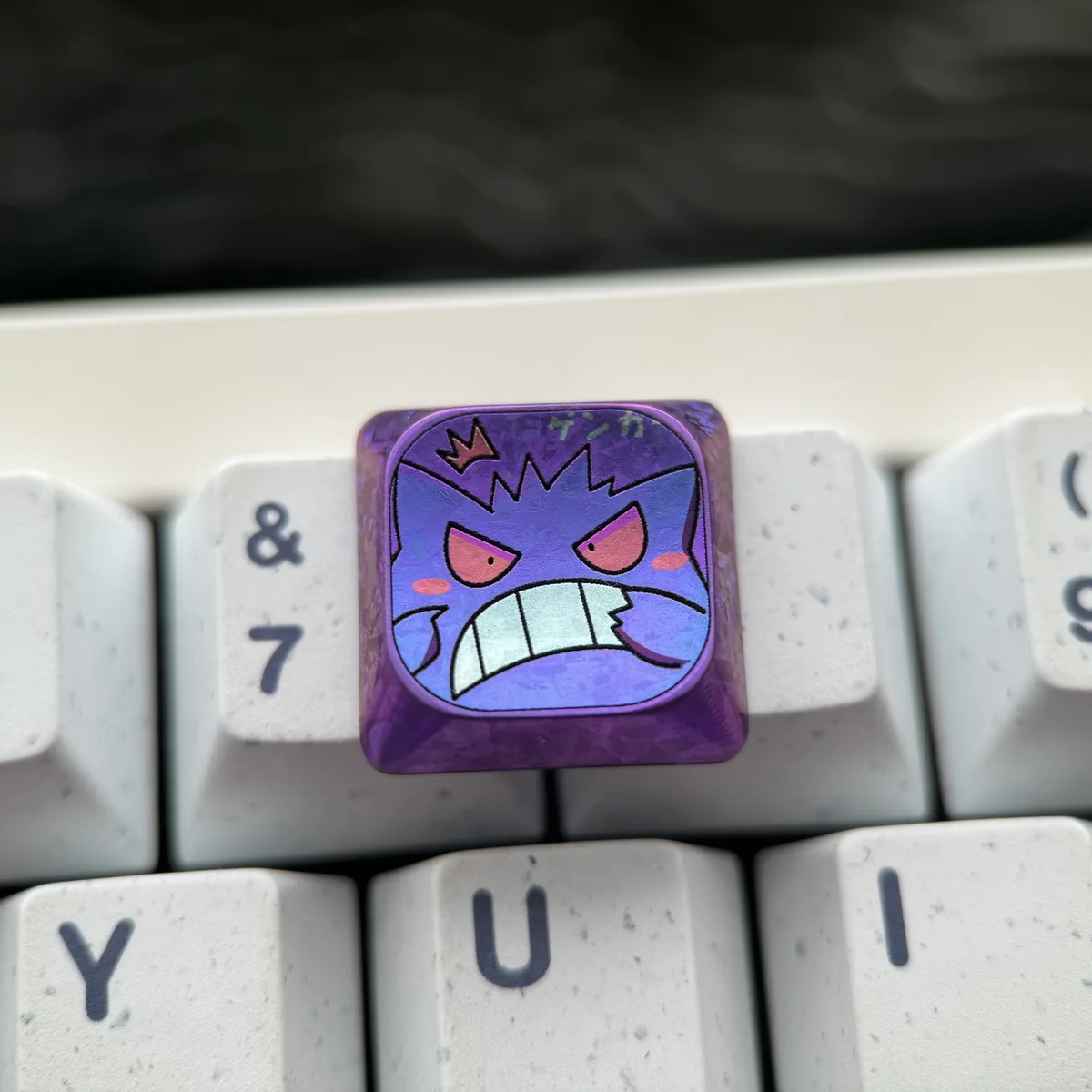 An artistic shot of the premium Gengar titanium low-profile keycap, revealing its intricately sculpted mischievous character from a different perspective view.