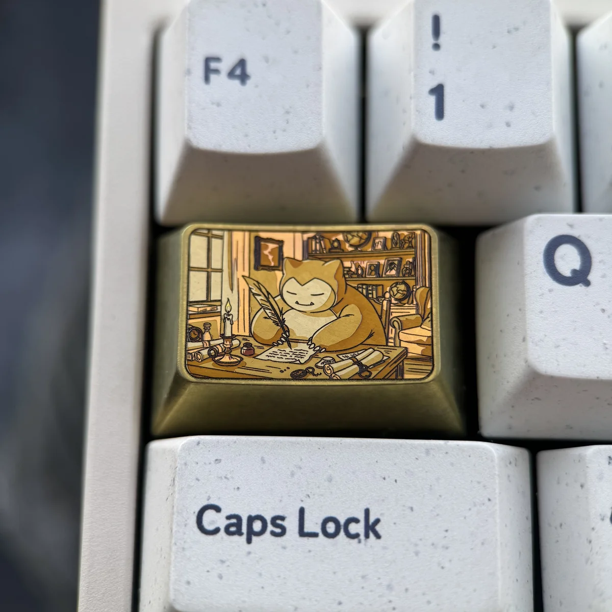 Close-up view of the Golden Snorlax titanium keycap, showcasing its lustrous golden finish and intricate Pokemon charm design from a unique angle.