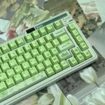 Artistic display of nature-inspired Greenery PBT keycaps, showcasing their tranquil hues and Cherry profile from various angles for an organic desktop aesthestic.