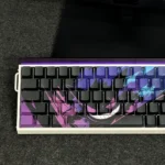 A close-up of the iconic Gengar backlit artisan keycap set, meticulously sculpted from PBT, showcasing its mischievous glowing purple details from a dynamic angles.