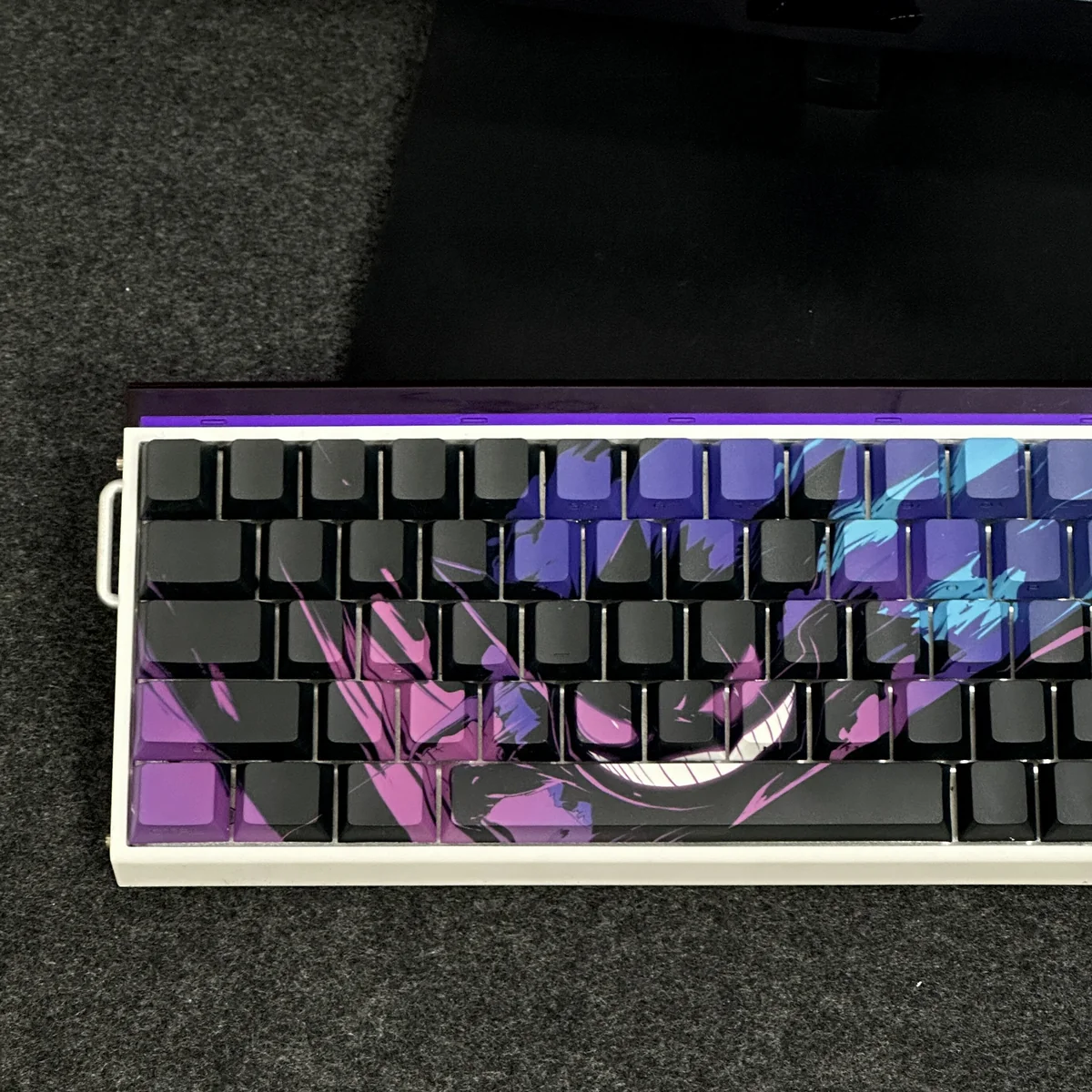 A close-up of the iconic Gengar backlit artisan keycap set, meticulously sculpted from PBT, showcasing its mischievous glowing purple details from a dynamic angles.