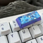 Premium titanium Overwatch Kiriko keycap showcasing its sleek metallic finish and detailed Swift Spirit design from multiple angles.