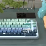 Close-up views of the Serene Wind Artistic Dye-Sub PBT Keycap Set, showcasing tranquil natural landscape and cloud motifs in soothing colors for serene design.