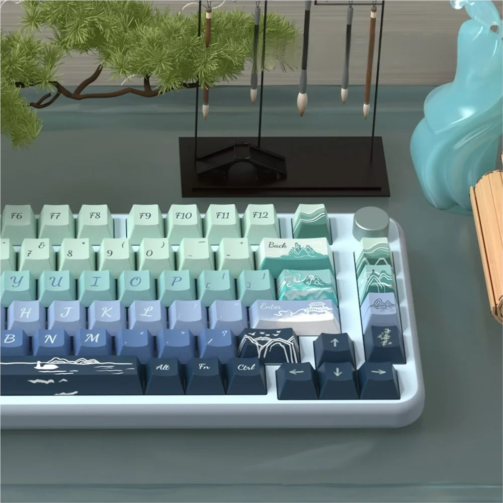Close-up views of the Serene Wind Artistic Dye-Sub PBT Keycap Set, showcasing tranquil natural landscape and cloud motifs in soothing colors for serene design.