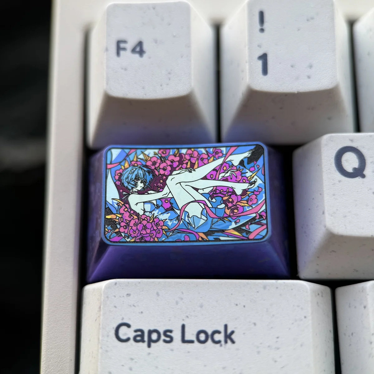 Close-up of the iconic Rei Ayanami Titanium Artisan Keycap (1.5U Tab) showcasing its vibrant colors and lustrous finish from a unique angle.