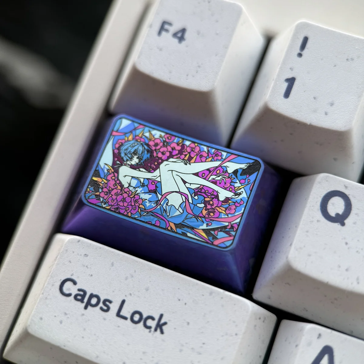 Detailed view of the iconic Rei Ayanami titanium artisan keycap, showcasing its vibrant colors and lustrous finish from a dynamic angle.