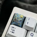 A close-up view of the Van Gogh Starry Night Titanium ESC keycap, showcasing its swirling cosmic blues and yellows from a unique angle.