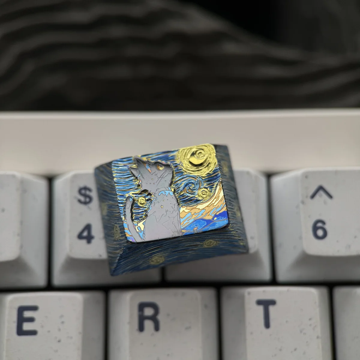 Angled view of a handcrafted Mystical Cat Titanium Artisan Keycap, showcasing its shimmering celestial cat design against a starry night sky.