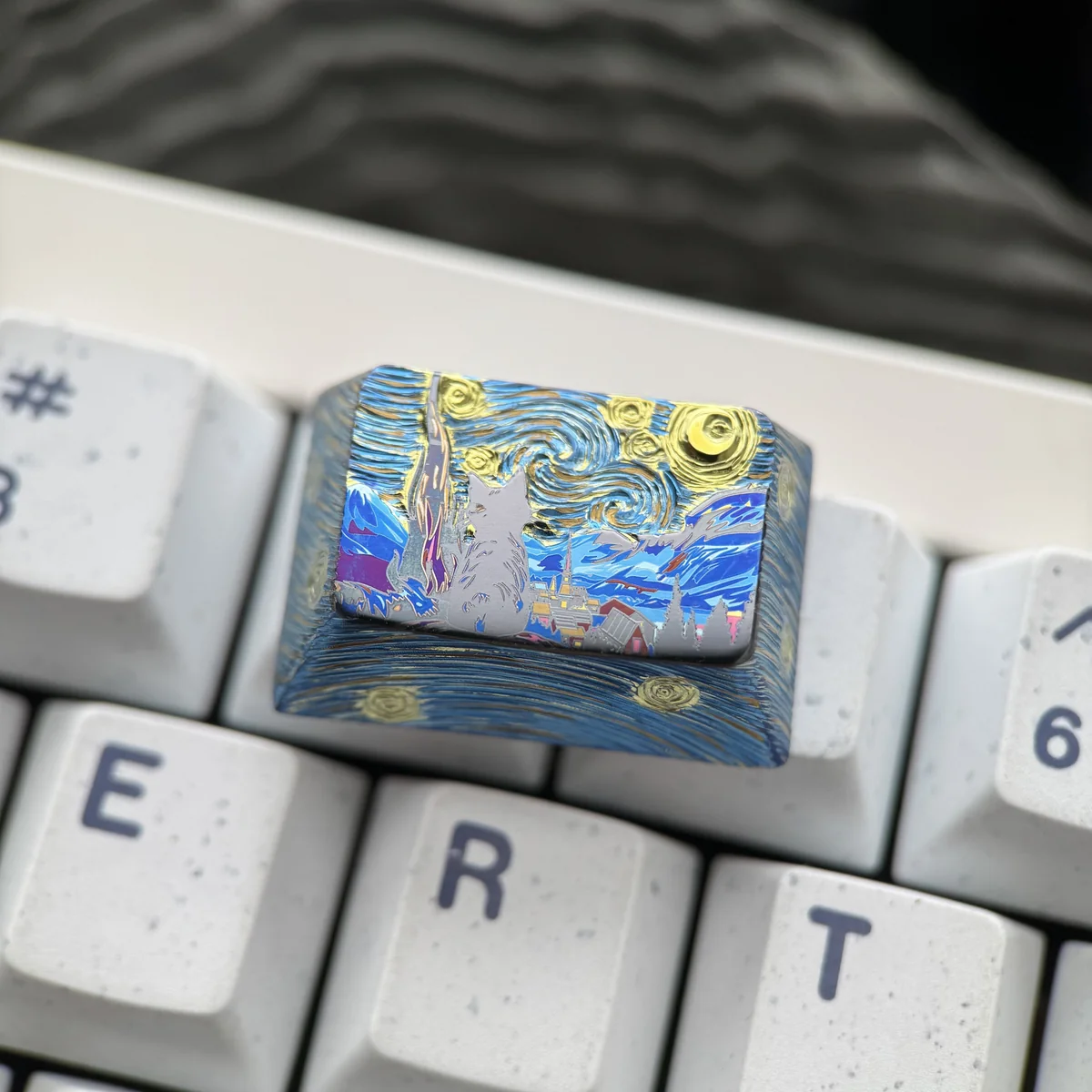 A handcrafted Cosmic Cat Tab Titanium Keycap, featuring a unique cat gazing into a shimmering cosmic galaxy. Premium artisan keyboard art.