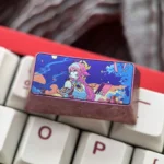 Close-up of the premium Yae Miko titanium ice-crystal keycap, showcasing its vibrant Genshin Impact character motif and iridescent anodized finish.