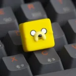 "Playful, handcrafted translucent resin Adventure Time Jake ESC keycap, glowing vibrantly with unique cartoon charm."