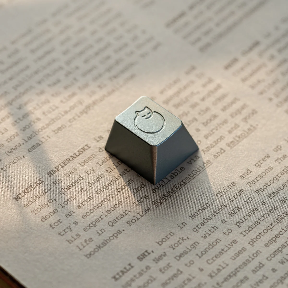 An angled view of the handcrafted aluminum sleeping cat artisan ESC keycap, revealing its serene metallic sheen and delicate, whimsical artistry.