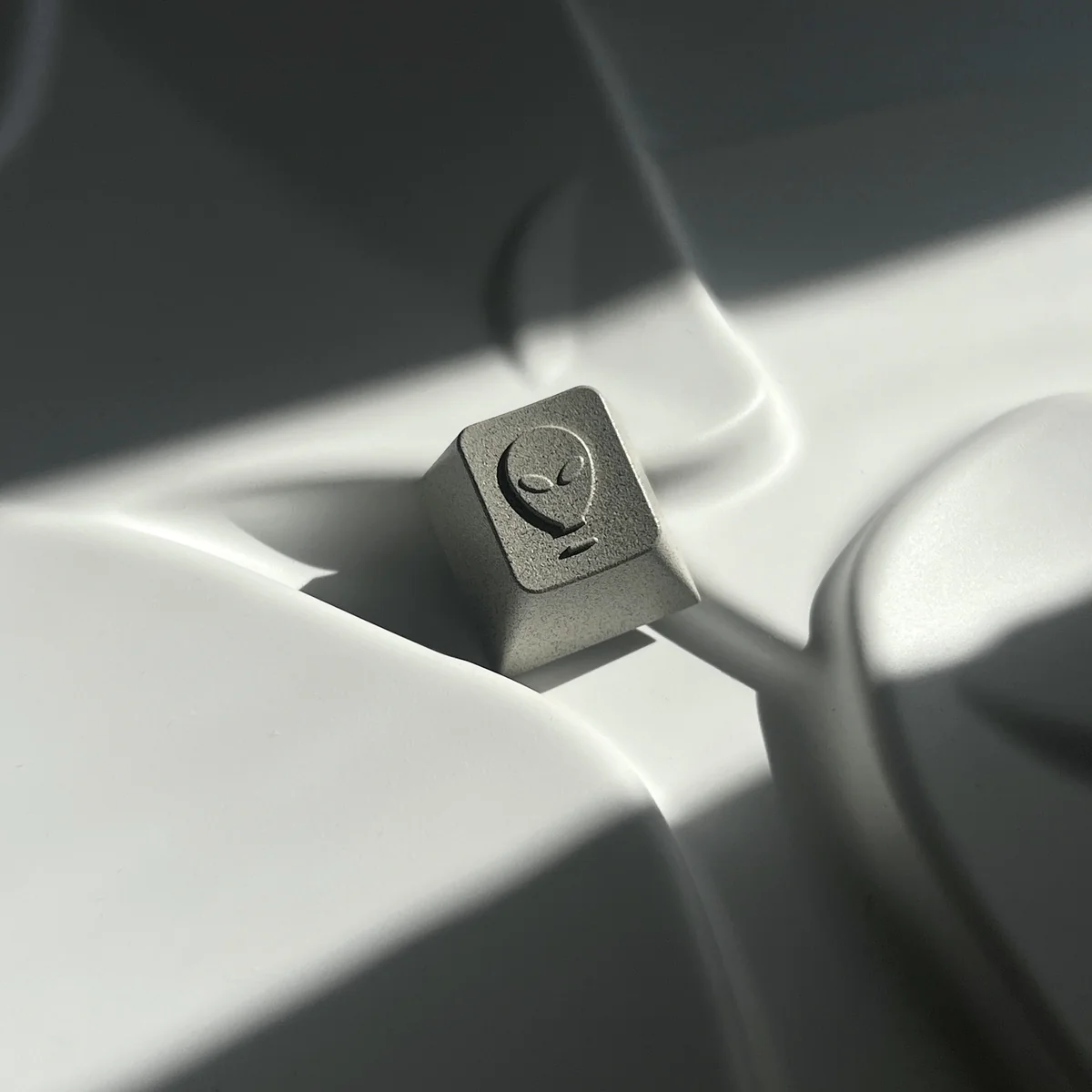 Premium CNC aluminum artisan keycap, showcasing its pyramid and alien designs from a distinct angle. Highlights durable metallic craftsmanship.