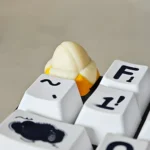 Close-up of a whimsical handcrafted banana resin keycap, showcasing its vibrant yellow miniature fruit design from multiple playful angles, ideal for fruit lovers.