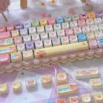Close-up view of the whimsical bear doll keycap set from a side angle, showcasing the charming PBT MOA profile and playful cartoon design.