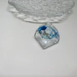 Nature's Bloom Butterfly Transparent Keycaps featuring a delicate dried daisy embedded in vibrant blue resin, showcasing artistic craftsmanship design.