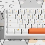 Vibrant, adorable Calico Cat PBT dye-sub Keycaps Set, shown from various angles. Warm hues create a whimsical, comforting desk.