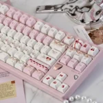Close-up of Cherry Cake PBT keycaps set, featuring charming pastel pinks and playful cherry and cake designs, highlighting durable PBT quality for a sweet touch.