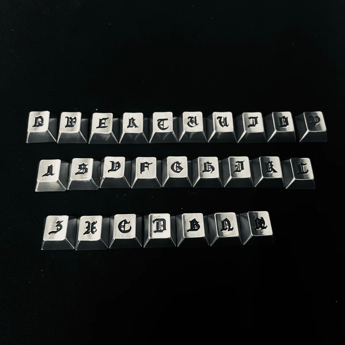 Close-up of handcrafted Gothic alphabet keycaps set, showcasing intricate medieval-inspired artistry and a dark, mystical aesthetic from the Timeless design.