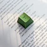 Vibrant Spring Bud Green Aluminum Artisan Keycap, Cherry R4, displayed from various angles, emphasizing its sleek metallic finish and intricately sculpted design.