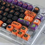 Vibrant Halloween PBT dye-sub keycaps set for mechanical keyboards, featuring playful spooky pumpkins, whimsical ghosts, and bats on dark keys. A festive design.