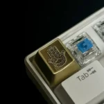 Hamsa Artisan Keycap in polished brass, showcasing intricate mystical metalwork from a different angle, symbolizing elegant protection.