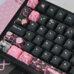 Close-up views of the unique Hello Kitty PBT dye-sub keycap set, showcasing its sweet and edgy black and pink design from various angles. Ideal for customization.