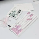 Close-up of handcrafted Hello Kitty cherry profile accent keycaps in vibrant pink and white, showcasing iconic characters from multiple angles with premium.