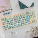 A unique angle of vibrant Hatsune Miku PBT keycaps set, showcasing crisp dye-sublimated Vocaloid character art and playful pop culture aesthetics.