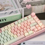 Whimsical Pink Gradient Melon MOA PBT Keycap Set. Soft pastel pink-to-white colors, sweet melon inspired. Cute, playful aesthetic, shown from various angle.