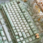 Tranquil Moss Whisper PBT dye-sub keycaps set presented from various angles, revealing their serene moss-green and earthy tones for a nature-inspired design.