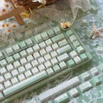 Tranquil Moss Whisper PBT Dye-Sub Keycaps Set. Gallery views highlight serene moss-green, earthy tones, and nature-inspired art.
