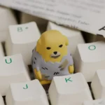 Nudaeng Dog Artisan Keycap, from a new angle, highlights its adorable cartoon dog and playful food details for vibrant keyboard color.