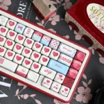 Sweet Cherry PBT keycap set for mechanical keyboards, artistically displayed from various angles, highlighting its durable PBT and nostalgic pastel.