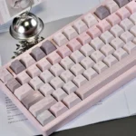 Pink PBT Keycap Set. Durable PBT, serene pastel pink, and 'Gentle World' graphics in Cherry profile create a calming desktop.