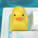 A close-up view of a handcrafted resin little yellow duck keycap, showcasing its whimsical details and playful charm from a unique angle, perfect for animal lovers.