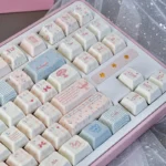 Rococo PBT Dye-Sub keycap set, showcasing multiple keys with delicate pastel floral patterns and ornate scrollwork, ready for an opulent keyboard.